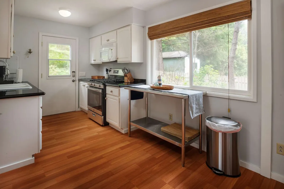 A warm, welcoming kitchen featuring stainless steel appliances, a large window letting in natural light, and a spacious wooden countertop. The scene hints at family gatherings, home-cooked meals, and the comforts of a peaceful retreat after a day of exploring nearby attractions.
