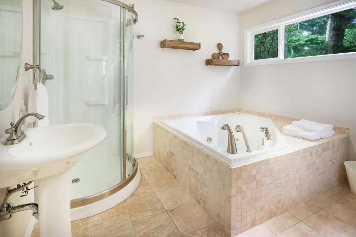 A tranquil bathroom scene featuring a spacious shower area, bathtub, and neatly arranged shelves. The clean, organized layout hints at the presence of laundry facilities nearby and the ease of cleaning up after outdoor adventures.
